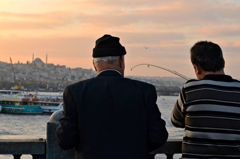 Anglers on Galata Bridge with a view of the Sueleymaniye Mosque at sunset