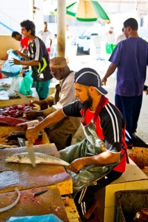 Men descale the fish for cash and process them into practical units with large cleavers