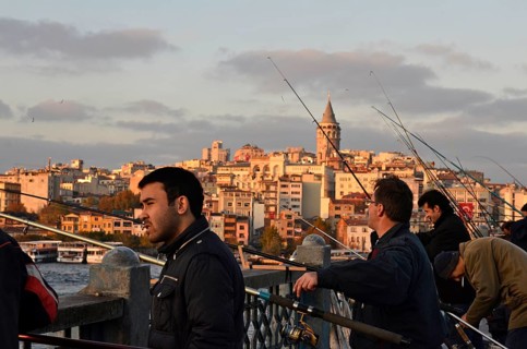 Anglers at the Golden Horn on Galata Bridge with view the Galata Tower at sunset