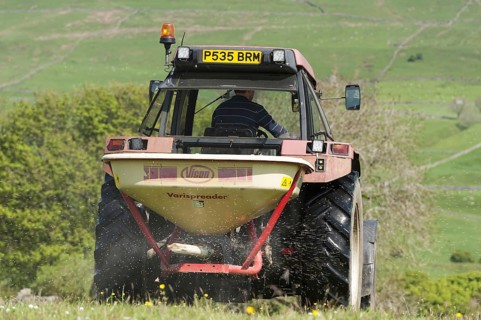 Speading fertiliser on a traditional Dales meadow with a Case International tractor. Hawes