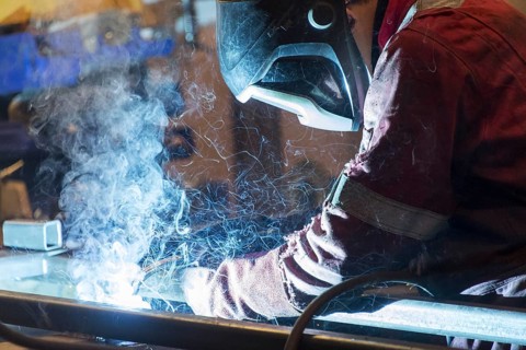 Factory worker welding in a manufacturing plant