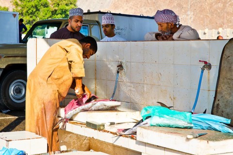 Man descales fish for cash and processes them into convenient units with large cleavers