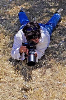 Photographer lying on her stomach with telephoto