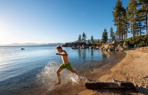 Young man running in the water on a sandy beach