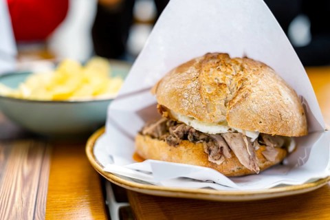 Delicious bun with delicate piglet and egg with chips aside