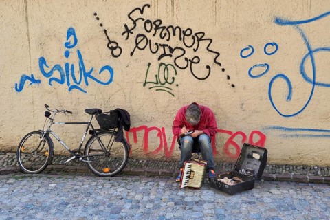 Sitting street musician with harmonium making notes
