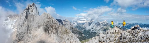 Two hikers in front of alpine panorama