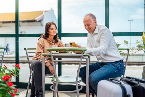 A couple of travelers drinking coffee and checking something on the phone