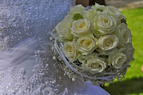 Wedding dress and bridal bouquet of yellow roses and pearl necklace
