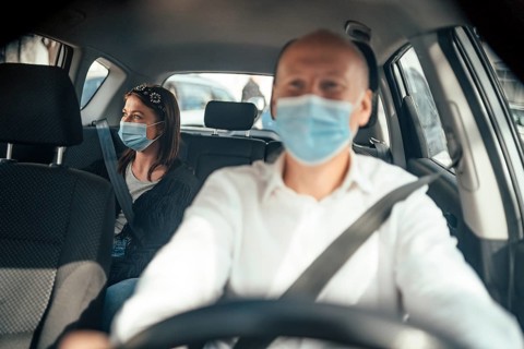 Taxi driver in a mask with a female client on the back seat wearing mask