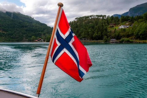 The Norwegian flag flies at the stern of a boat on Lovatnet