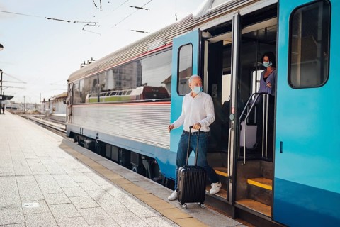Tourists with suitcases and masks on exiting the train