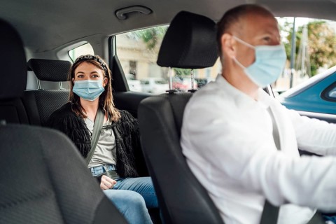 Taxi driver in a mask with a female client