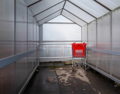 Last red shopping trolley under a plastic roof