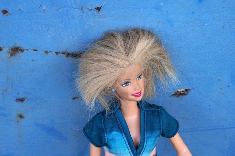 Barbie doll leaning against blue metal plate