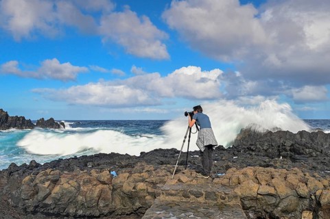 Photographer taking pictures in strong waves at the sea
