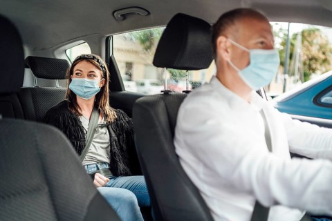 Taxi driver in a mask with a female client on the back seat wearing mask