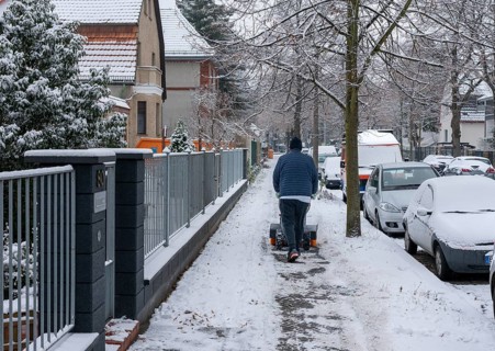 Caretaker removing snow and ice from a pavement