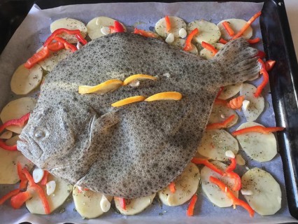 Fresh turbot on a bed of potatoes and strips of paprika