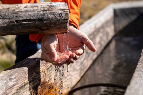 Hiker draws water from a well