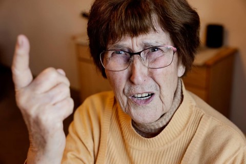 Angry senior citizen threatens with her raised index finger