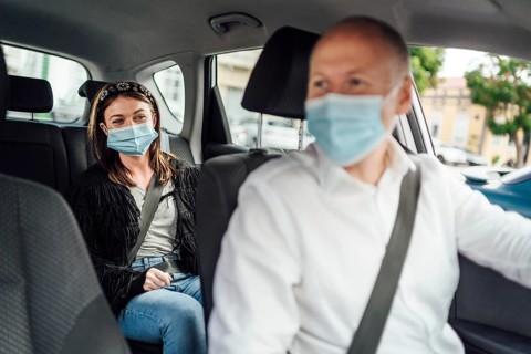 Taxi driver in a mask with a female client on the back seat wearing mask