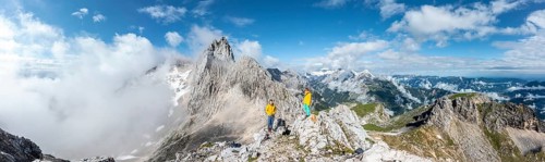 Two hikers in front of alpine panorama
