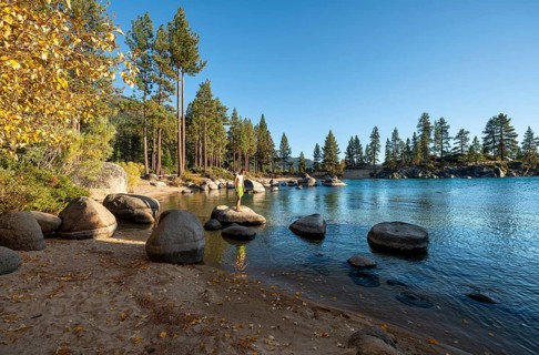 Young man in swimming trunks on round stones in the water