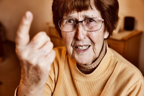 Angry senior citizen threatens with her raised index finger