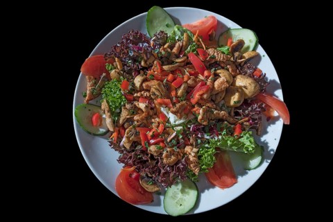 Salad with fried turkey strips and fresh mushrooms on a black base