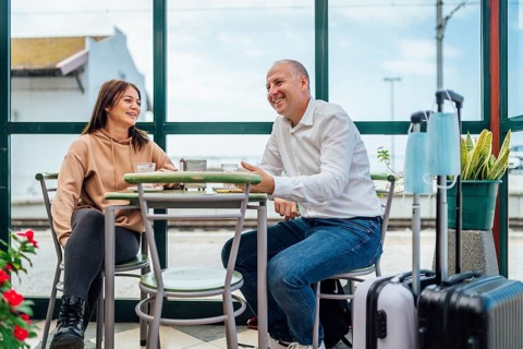 A couple of travelers drinking coffee and checking something on the phone