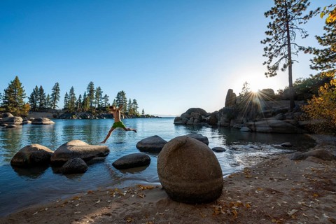 Young man in swimming trunks jumps from stone to stone