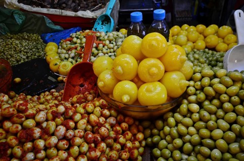 Bowl of Moroccan salted lemons on mountain with varieties of olives