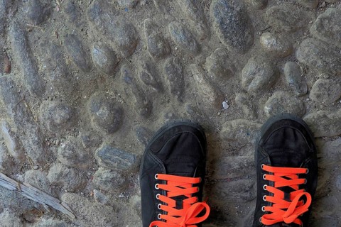 Black sports shoes with red shoe laces on street