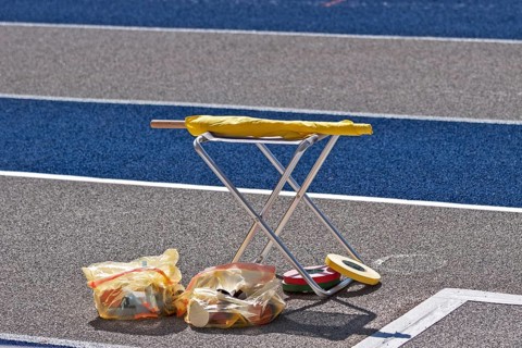 Stools and rubbish bags stand next to the tartan track at an athletics event in the Olympic Stadium