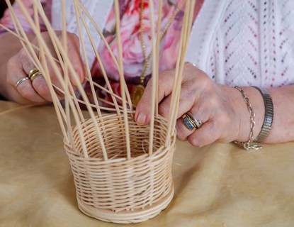 Hands of an 86-year-old senior citizen in a nursing home weaving a basket