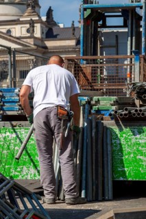 Construction worker loading a truck with scaffolding poles