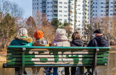 Senior citizens with a carer sitting on a wooden bench at the Segeluchbecken in the Maerkisches Viertel