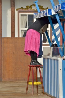 Woman in dirndl stands on stool and cleans
