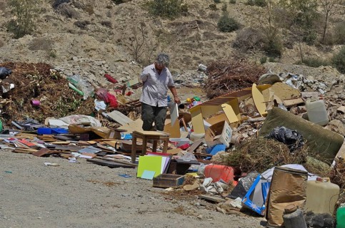 Old woman looking for useful things in rubbish heap