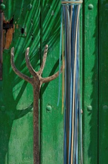 Wooden pitchfork leaning against green wooden door