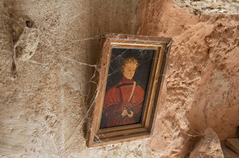 Golden picture frame with cobwebs on clay wall