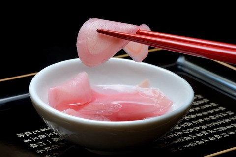 Sliced pickled ginger on chopsticks and in bowl