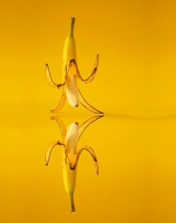 Banana with peel against a yellow background