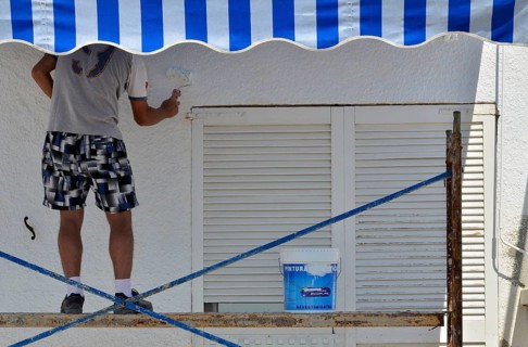 Painter on scaffolding painting house