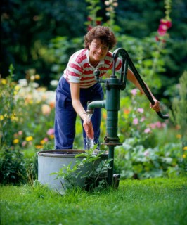 Woman pumps water in the garden