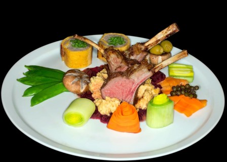 Pink roasted saddle of lamb on corn polenta with red wine onions and various vegetables