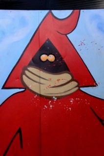 Red figure with hood and mouth guard sprayed on metal door
