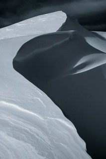 Snow cornice against a dark sky at the summit of Toreck