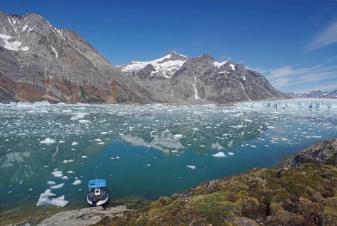 Small boat in a fjord with ice and icebergs